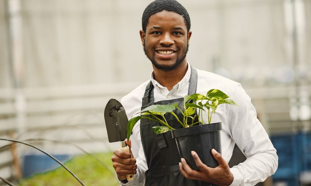 gardener-apron-african-guy-greenhouse-flowers-pot